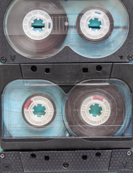 Two worn audio cassettes in a black and transparent case close-up. Top view