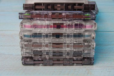 Mavi ahşap arka planda bir yığın ses kaseti. Manyetik filmi, silindirleri ve keçeli yastıkla basınç mekanizmasını görebilirsiniz. Yakın plan.