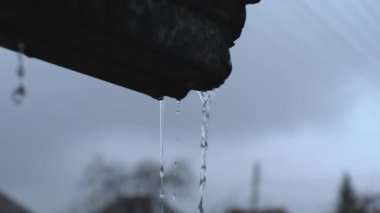 Metal bir oluktan iki akarsu akıntısı. Fırtınalı bir gökyüzünün arka planında