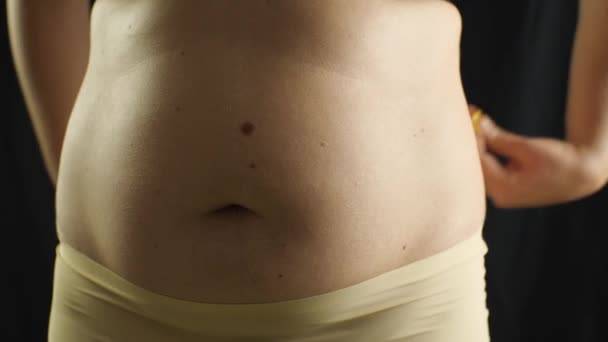 一个有大肚子的超重女人用带子前视镜进行测量 — 图库视频影像