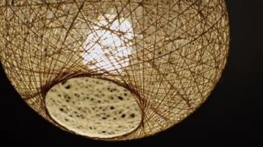 Siyah arka planda enerji tasarrufu sağlayan bir lambası olan ev yapımı iplikli bir abajur. Yakın plan.