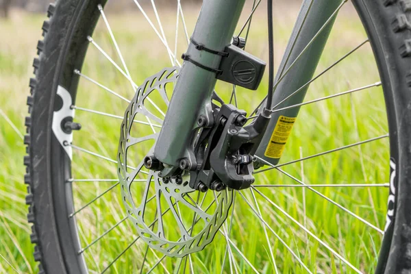山地自行车前轮大液压制动器转子 在绿草模糊的背景下 健康生活方式概念 — 图库照片