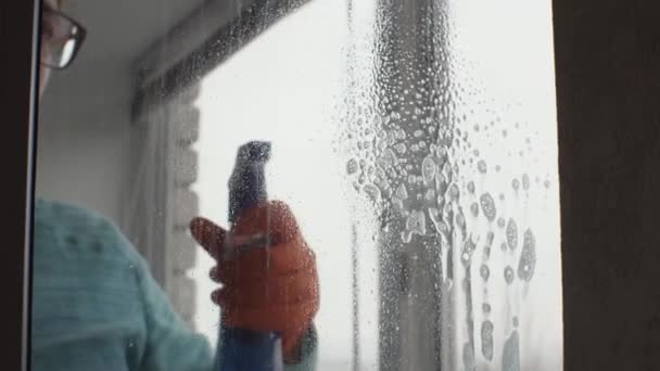 Ein Mädchen Einem Orangefarbenen Handschuh Sprüht Glasreiniger Auf Das Fenster — Stockvideo