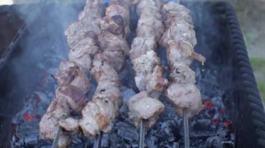 Şiş üzerindeki et parçaları eski paslı bir ızgarada kızartılır. Duman ve alevler yanıp sönüyor. Shashlik geleneksel bir Kafkas yemeğidir. Yakın plan.