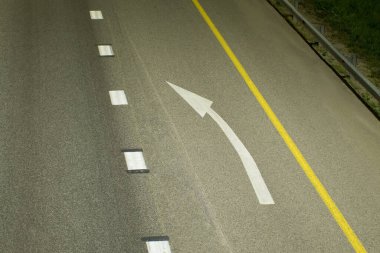 Asfalt üzerine beyaz bir ok çizilir, kırık bir çizgi ile katı sarı bir çizgi arasında. Üst görünüm