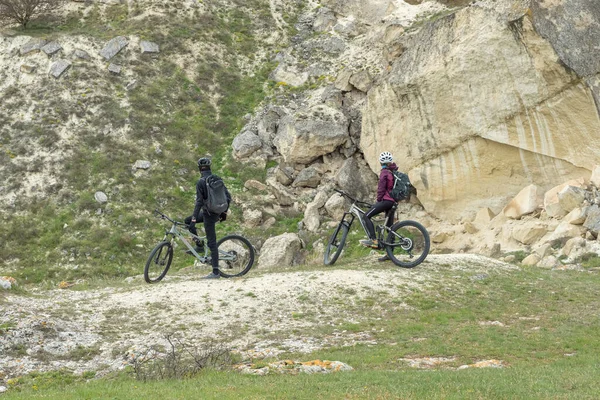两个骑自行车的人在山上望着岩石 背对着摄像机站着 — 图库照片