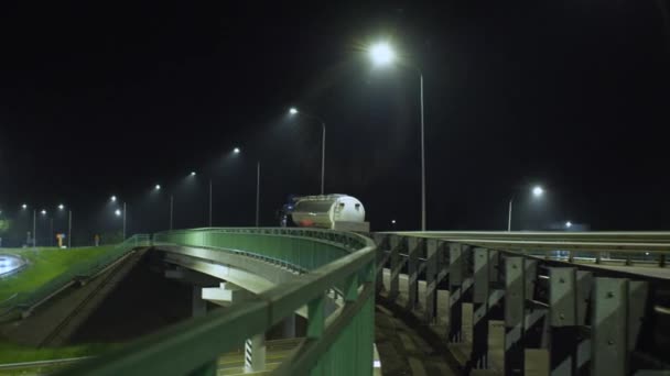 牵引机一种牵引机 带有水槽 沿着高耸的高架桥行驶 灯火通明摄像机从右移到左移 夜间射击 — 图库视频影像