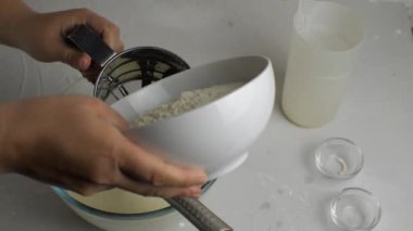 Kadın eli, kefir ve yumurtalarla şeffaf bir kâseye un karıştırıyor. Krep için hamur hazırlama