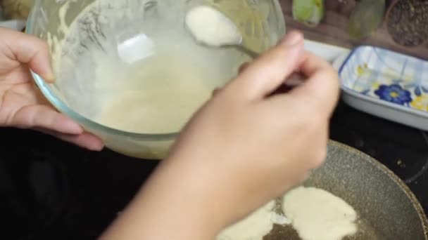 女手用勺子 把杯子里的面团倒入油锅 在家里厨房里做煎饼的过程 — 图库视频影像
