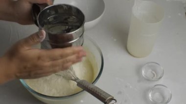 Unu şeffaf bir kâseye yerleştir ve hamuru krep için çırpıcı ile karıştır. Yakın plan.