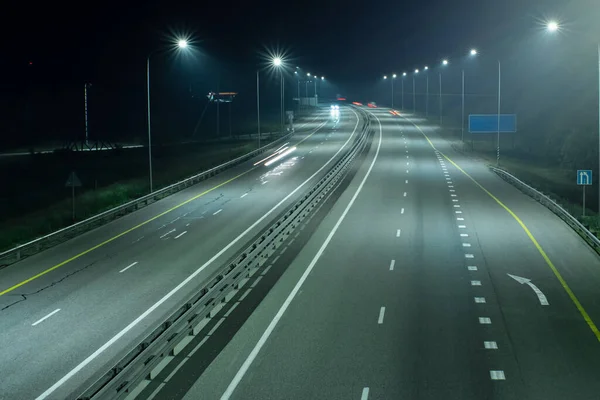 High-speed suburban highway in the light of streetlights. There is a white marking arrow on the asphalt. Night scenes