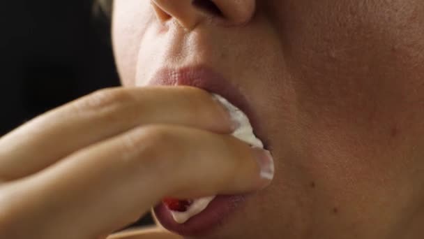 イチゴをクリームで噛んだ女性のクローズアップ 唇にクリームの跡が残っています 女の子ワイプ彼女の唇とともに彼女の指 — ストック動画