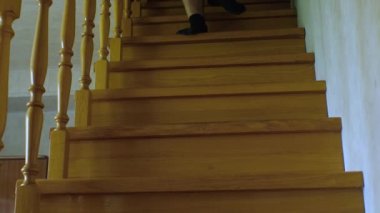 Şortlu ve çoraplı bir adam ahşap ev merdivenlerinden aşağı iniyor. Sabit çerçeve