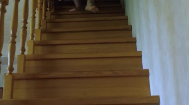 Çıplak ayaklı şortlu bir adam ahşap ev merdivenlerinden iniyor. Sabit çerçeve