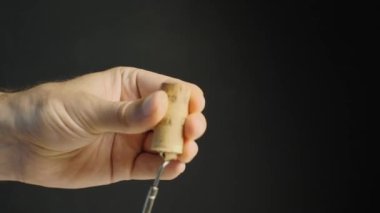 Erkeklerin elleri şarap mantarından tirbuşon çıkarır. Yakın plan. Siyah arkaplan