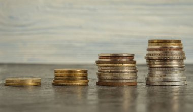 Yükselen sırayla dört madeni para yığını siyah bir arkaplanda yatıyor. İş planlama, finans ve tasarruf kavramı. Yakın plan.