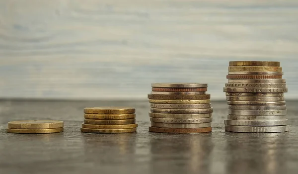 Yükselen sırayla dört madeni para yığını siyah bir arkaplanda yatıyor. İş planlama, finans ve tasarruf kavramı. Yakın plan.