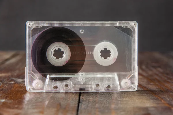 Een Audiocassette Een Doorzichtige Krasbak Staat Een Bruine Houten Achtergrond — Stockfoto