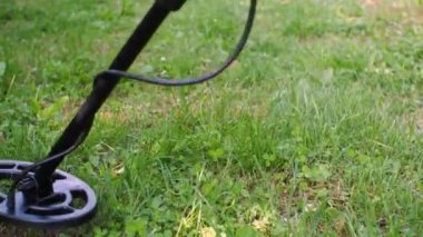 Bir metal detektörü ödül araması için yeşil çimlerin üzerinde sağa sola hareket ediyor.