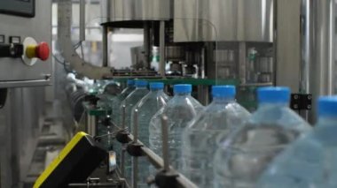 Su üretim hattı. Beş litrelik dolu plastik şişeler taşıyıcı boyunca hareket ediyor. Fabrikada maden suyu üretimi
