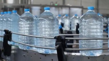 Su üretim hattı. Beş litrelik su şişeleri taşıyıcı boyunca hareket ediyor. Yiyecek işleme tesisinde içme suyu üretimi