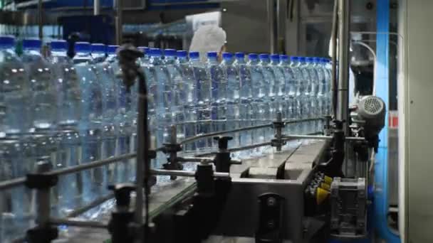 飲料水の生産のための買い物 コンベア上で水ボトルを移動します 食品加工工場でのミネラルウォーターの製造 — ストック動画