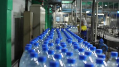 Mavi kapaklı plastik şişeler üretim hattı boyunca beş sıra halinde ilerliyorlar. Gıda endüstrisinde maden suyu üretimi