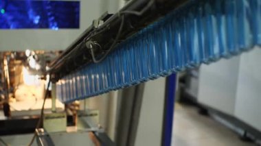 Mavi plastik preformlar konveyör boyunca şişe üfleme makinesine gönderilir. İçme ve maden suyu üretimi için bitki.