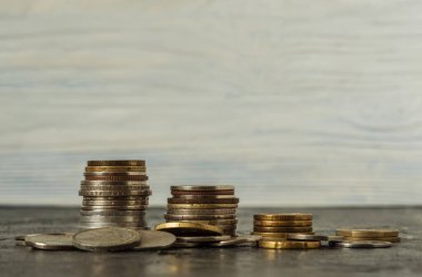 Siyah arkaplanda, alçalmakta olan dört adet bozuk para yığını var. Bozukluklar ön tarafa saçılmış. İş planlaması, finans ve tasarruf kavramı