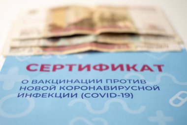 Aşı sertifikası ve paranın yakın çekimi. Seçici odaklanma. Dolandırıcılar tarafından sertifika satışı. Rusça yazı: COVID-19 'a karşı aşı sertifikası