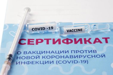 Aşı sertifikası, şırınga ve aşıyla birlikte iki ampul yakın çekim. Çeviri: yeni bir koronavirüs enfeksiyonuna karşı aşı sertifikası COVID-19