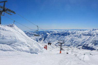 Gürcistan, Gudauri, 8 Mart 2013: Arkaplandaki kar örtülü zirveler ve mavi gökyüzü. Aktif kış tatili kavramı