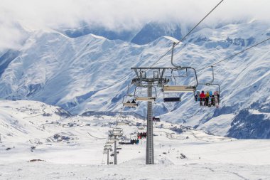 Gürcistan, Gudauri, 8 Mart 2013: Kayak merkezindeki insanlarla birlikte. Sis kaplı karla kaplı tepelerin arka planına karşı. Aktif kış tatili kavramı
