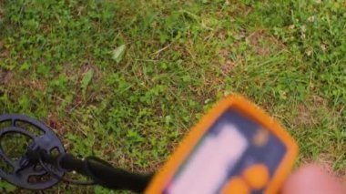 Bir adamın eli yerde metal detektörü hareket ettiriyor. Birinci şahıstan en iyi görüntü. Metal Arama Konsepti