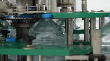 Kapak makinesinde beş litrelik şişeler var. Gıda işleme tesisinde içme suyu üretim hattı