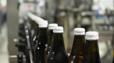 Cam su şişelerinin üst kısımları dükkandaki bir taşıyıcıda hareket ediyor. Yiyecek endüstrisinde içme suyu üretimi