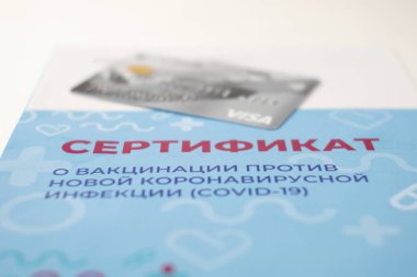 Krasnodar, Krasnodar Bölgesi, Rusya, 5 Temmuz 2021: Aşı sertifikası ve Visa banka kartının yakın çekimi. Dolandırıcılar tarafından sahte formlar satılıyor. Seçici odak