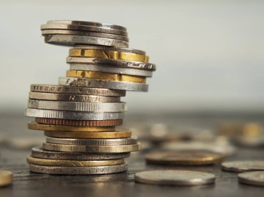 Farklı ülkelerin paraları farklı pozisyonlarda üst üste istiflenmiştir. Siyah arka plan ve diğer madeni paralar üzerinde. Tasarruf kavramı. Yakın plan.