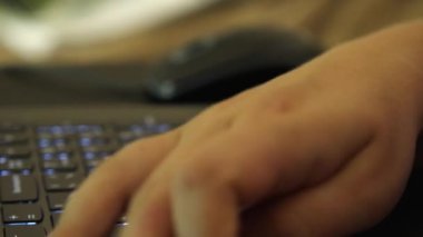 Dizüstü bilgisayarın klavyesine yazı yazan parmaklar. Kamera düğmeler boyunca hareket eder. Evden uzak çalışma kavramı