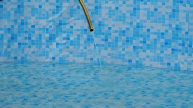 Water flows from a dirty garden hose, filling the pool. The concept of water entertainment during the summer holidays