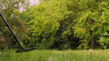 Arka bahçesinde metal dedektörü olan hazine avı. Cihazı olan bir adam bozuk para arıyor.