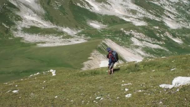 Sırt Çantalı Bir Adam Dağlarda Çimenli Bir Yamaçtan Aşağı Yuvarlanıyor — Stok video