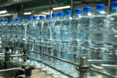 Su plastik şişelerde, mavi kapaklı taşıma bandında. Gıda üretimi