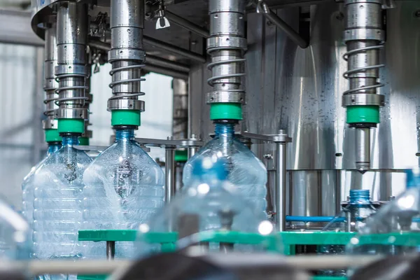İçme suyunu beş litrelik plastik şişelerde şişelemek için otomatik hat. Şişeyi otomatik dolgu makinesiyle doldurma işlemi. Gıda üretimi