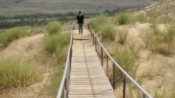 Een Meisje Loopt Een Houten Platform Het Gele Zand Gelegd — Stockvideo