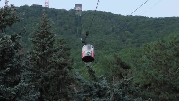 一辆红色的旧缆车的特写镜头 人们在一个巨大的云杉和绿色森林的背景下向下移动 2021年8月2日 俄罗斯斯塔夫罗波尔地区皮亚季戈尔斯克 — 图库视频影像