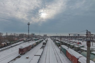 Yukarıdan bir tren istasyonu manzarası. Yük vagonları ve platformlar karla kaplı. Gökyüzü bulutlarla kaplı. Demiryolu taşımacılığı kavramı. Krasnodar, Rusya, 18 Şubat 2021