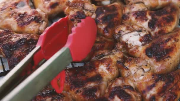 从烤架上取下炸鸡翅的厨房钳子的特写 很好吃的炸鸡翅户外烹调的概念 — 图库视频影像