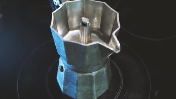 Алюминиевая кофеварка Geyser стоит на черной электрической плите. Процесс приготовления вкусного кофе дома. — стоковое видео