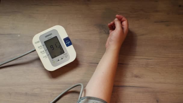 Kvinnas Hand Med Blodtrycksmätare Mot Bakgrund Ett Träbord Skärmen Tonometern — Stockvideo